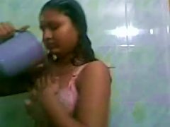 A Teenage Girl With A Dark Complexion And Wearing Only A Towel Is Seen Standing In The Bathroom While Her Boyfriend Washes Her Hair.